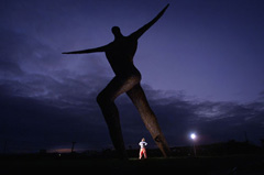 Night shot of Serena standing under the Willow Man at night